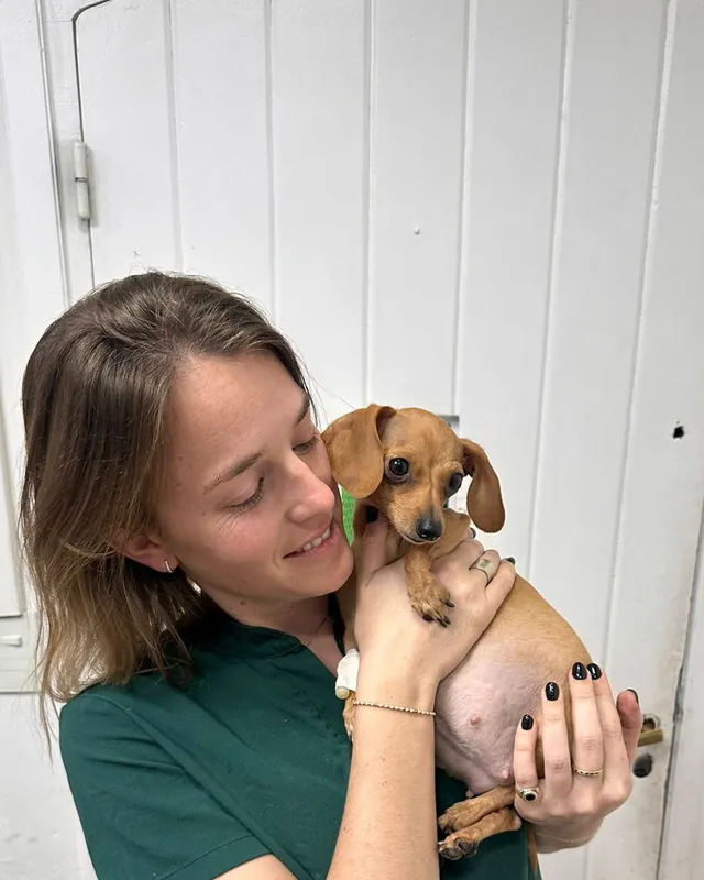 Jazmín con un cachorro salchicha en brazos